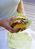 Woman holding chicken burger with rocket mayonnaise