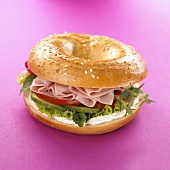 Bagel with soft cheese & turkey breast against pink background