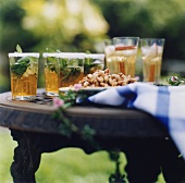 Mehrere Drinks mit Rum und Minze auf einem Gartentisch
