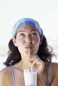 Junge Frau trinkt Milchshake am Strand