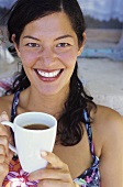 Junge Frau trinkt Kaffee am Strand