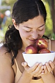 Young woman holding bowl of nectarines