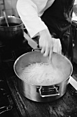 Chef stirring spaghetti in a pan