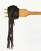Cooked black spaghetti on wooden fork