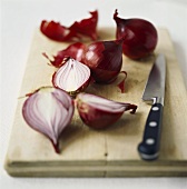 Red onions on chopping board with knife