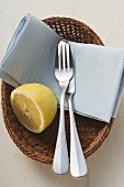 Fish knife & fork, blue fabric napkin & lemon in bread basket