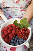 Woman holding assorted berries in a strainer