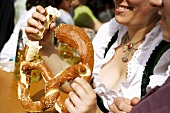 Woman in national dress eating soft pretzel (Oktoberfest, Munich)