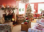 Weihnachtlich dekoriertes Wohnzimmer mit geschmücktem Christbaum, Kamin, Sofa, Sesseln & Kronleuchter