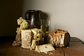 Still life with hard cheese, bread, grapes and white wine
