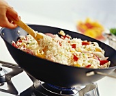 Rice and vegetables being fried in a wok