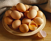 Brown eggs on plate, one egg broken open