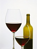 Two glasses of red wine and red wine bottle in background