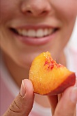 Woman holding a piece of peach