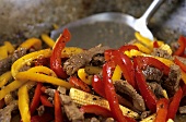Strips of beef and strips of pepper in a frying pan