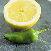 Grüne Pfefferschote und Zitronenhälfte