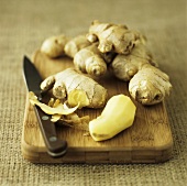 Ginger root with knife on wooden board