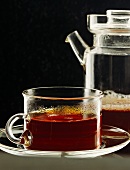 Eine Tasse Tee, im Hintergrund Teekanne