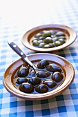 Black and green olives in small bowls on checked cover