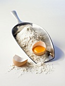 Egg, broken open, flour and flour scoop