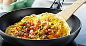 Omelette with pieces of tomato and chives in frying pan