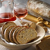 Aufgschnittenes Walnuss-Ciabatta, dahinter Roséwein