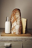 Milchflasche, Brot und Käse auf einem Holzschrank