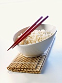 Cooked rice in a bowl with red chopsticks