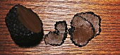 Trüffelknolle und Trüffelscheiben auf Holzuntergrund