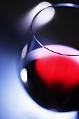 A glass of red wine against a blue background, close-up