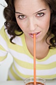 Woman drinking vegetable juice through a straw