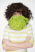 Woman with lettuce in front of her mouth