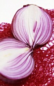A halved red onion on a net