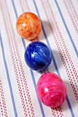 Three coloured Easter eggs on striped cloth