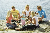 Junge Leute mit Kind beim Picknick am Meer
