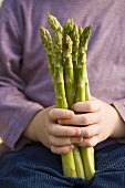 Child holding green asparagus in its hands