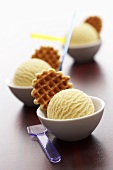 A scoop of vanilla ice cream with waffle in small bowl