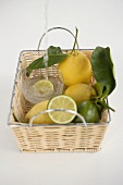 A glass of mineral water in a basket with lemons and limes