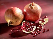 Two pomegranates and piece of pomegranate with seeds