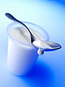 Spoon lying across an open yoghurt pot