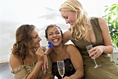 Three laughing women holding glasses of sparkling wine