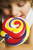 Child biting into a coloured lollipop