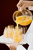 Chambermaid pouring orange juice into a glass