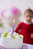Small kiwi coconut cake with one candle, child in background