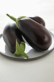 Three aubergines on white plate