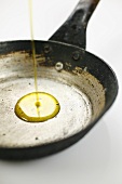 Pouring olive oil into an old frying pan