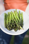 Woman holding plate of grilled asparagus