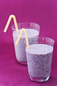 Two glasses of blueberry buttermilk with straws