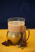 Ein Glas Chai-Tee, umgeben von Gewürzen