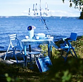 Table and chairs with hanging chandelier by a lake